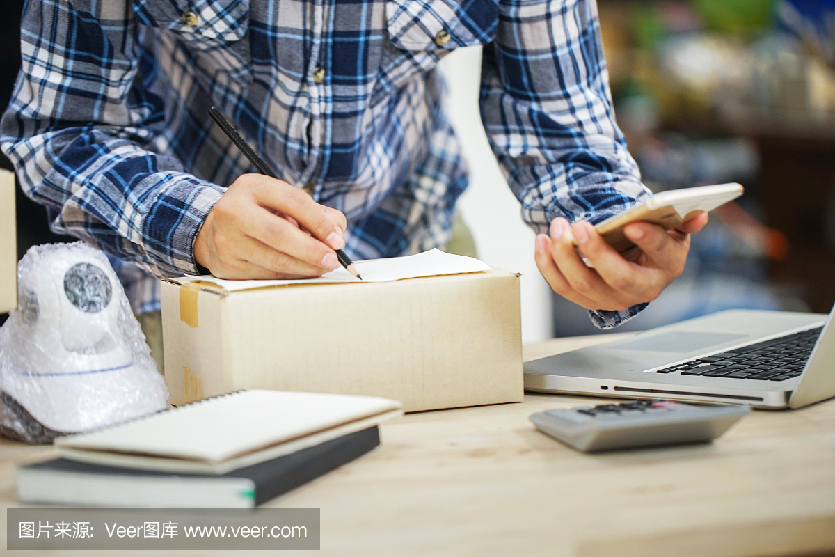 年輕的創(chuàng)業(yè)小企業(yè)主在工作場所的盒子里裝攝像頭閉路電視。自由職業(yè)者銷售者準(zhǔn)備產(chǎn)品的包裝過程在家里。網(wǎng)絡(luò)銷售,網(wǎng)絡(luò)營銷,